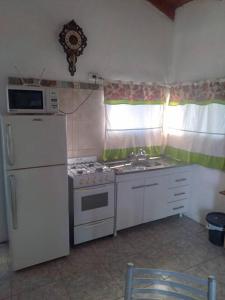 La cuisine est équipée d'une cuisinière, d'un réfrigérateur et d'un four micro-ondes. dans l'établissement Casa en la Colonia - PetFriendly, à Concepción del Uruguay
