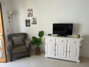 a tv sitting on top of a white cabinet next to a chair at Don Antonio Cristianos Beach Vivienda vacacional in Los Cristianos