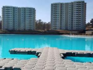 une grande piscine avec deux grands bâtiments en arrière-plan dans l'établissement Depto con piscina y laguna artificial en Las cruces, à Las Cruces