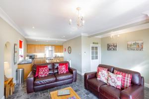 uma sala de estar com dois sofás de couro e uma cozinha em Rowan Tree Cottage with Hot Tub em Cupar