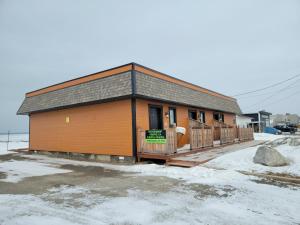 un pequeño edificio con un cartel en la nieve en Motel Au Bord de l'Eau, en Rimouski
