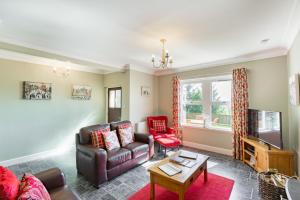uma sala de estar com um sofá e uma televisão em Rowan Tree Cottage with Hot Tub em Cupar