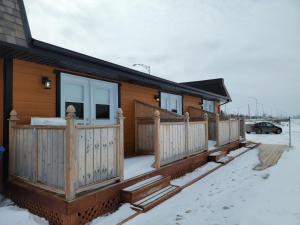 une maison avec une terrasse en bois dans la neige dans l'établissement Motel Au Bord de l'Eau, à Rimouski