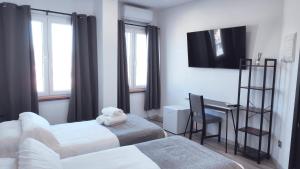a room with two beds and a desk and a television at Hostal Doña Isabel in Majadahonda