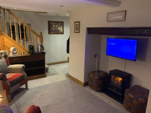 a living room with a fireplace and a flat screen tv at Broombush B & B in Aberhafesp