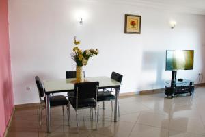 a dining room table with chairs and a vase with flowers at Residence Le Carat Silverline in Douala