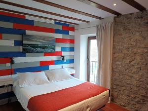 a bedroom with a colorful wall with a bed at Posada Punta Liñera in San Vicente de la Barquera