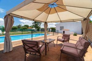 比利亚拉尔沃Finca Alonso的一个带大遮阳伞和椅子的庭院和一个游泳池