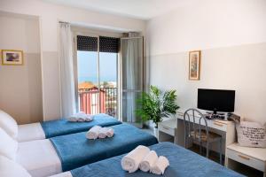 a room with two beds and a desk and a television at Hotel Selene - Vista Mare in Riccione