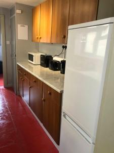 a white refrigerator in a kitchen with wooden cabinets at The Brougham House in Bath