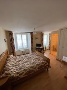 a bedroom with a large bed and a desk at Au Bon Accueil in Arvieu