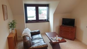 a living room with a leather couch and a television at Loch View, Lairg in Lairg