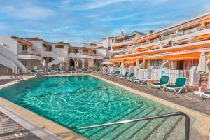 a swimming pool with chairs and a hotel at Lux and Cozy apartment in Los Cristianos