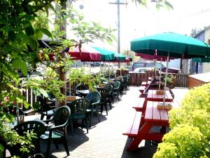 a row of tables and chairs with umbrellas on a sidewalk at McMenamins Olympic Club in Centralia