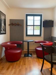 eine Bar mit roten Stühlen, einem Tisch und einem Fenster in der Unterkunft Double B in Erfurt