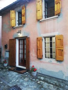 uma casa com portas e janelas de madeira e flores em La Chicca piccola casina in affitto nel Borgo Antico di Gaggio Montano BO em Gaggio Montano