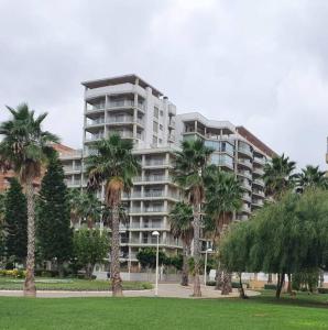 a large apartment building with palm trees in a park at Lorena Flat, 2 rooms 2 bath Seaview in Oropesa del Mar