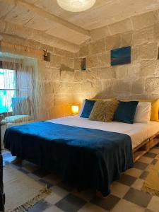 a bedroom with a large bed in a stone wall at Haven Farmhouse B&B in Għarb