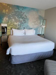 a bedroom with a large bed with a painting on the wall at Courtyard Boston Raynham in Raynham