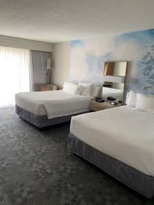 RaynhamにあるCourtyard Boston Raynhamのベッド2台と鏡が備わるホテルルームです。