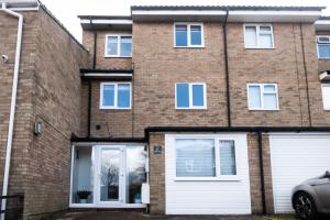 a brick house with two white garage doors at Town House Chantry - With Self Check In and Free Parking - Rooms at ipswichdigs in Ipswich