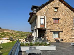 een stenen huis met een patio en een tafel bij Hotel Boutique Finca esencial in Villafranca del Bierzo