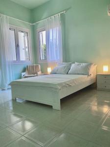 a large white bed in a room with two windows at Feels like home (Vari) in Vari