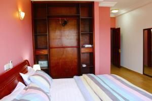 a bedroom with a bed and a wooden closet at Residence Le Carat Silverline in Douala