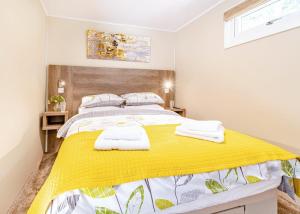 a bedroom with a yellow bed with towels on it at Woodland Lakes Boutique Lodges 
