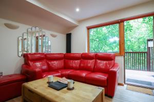 a red leather couch in a living room with a table at Lodge Nine for 6 with Hot Tub - Spa Resort in Devon in Chudleigh +66 photos