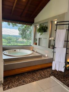 a large bathroom with a tub and a large window at Chalé Village Jângal in Machado