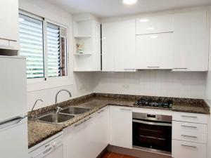 - une cuisine blanche avec des placards blancs et un évier dans l'établissement Villa Playa, à L'Ametlla de Mar