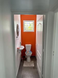 an orange bathroom with a toilet and a sink at VillaCalmflor in Sainte-Anne
