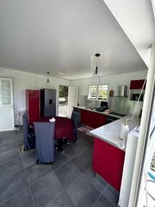 eine Küche mit roten Schränken und einem Tisch darin in der Unterkunft VillaCalmflor in Sainte-Anne