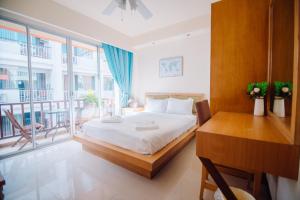 1 dormitorio con cama, escritorio y balcón en Patong Beach Side Hotel en Patong