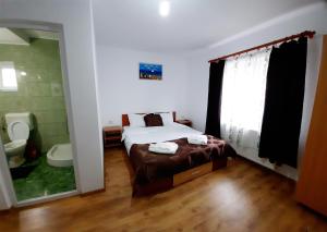 a bedroom with a bed and a bathroom with a toilet at Casa cu flori in Tuzla