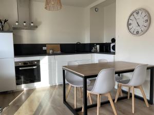 a kitchen with a table and chairs and a clock on the wall at Hyper Centre - 2 PIÈCES tout confort - Terrasse - ascenseur - in Cabourg