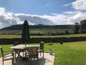 a table with an umbrella and chairs and a field at East Cottage at Parbroath Farm in Cupar