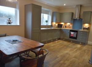 uma cozinha com uma mesa de madeira e um piso de madeira em East Cottage at Parbroath Farm em Cupar