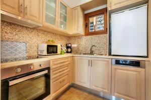 a kitchen with wooden cabinets and a microwave at Plaka Beach Cottages in Pláka