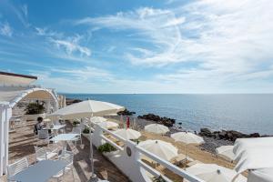 a beach with white chairs and umbrellas and the ocean at Hotel Cavalluccio Marino in Santa Marinella