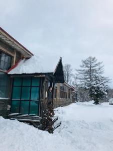 un hombre parado fuera de una casa en la nieve en Boken Kazoku, en Kutchan
