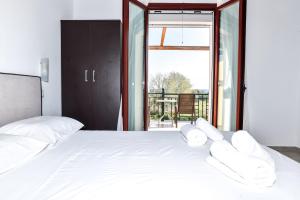 a bedroom with a white bed and a large window at Donna Dorato in Finikounta