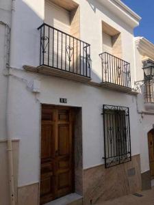 un edificio blanco con puerta de madera y balcón en La Casa de Tente, en Priego de Córdoba
