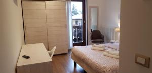 a bedroom with a bed and a table and a window at Garni San Lorenzo in Pinzolo