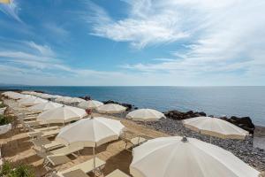 a row of white umbrellas on a beach with the ocean at Hotel Cavalluccio Marino in Santa Marinella