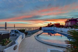 a swimming pool with a sunset in the background at Hotel Cavalluccio Marino in Santa Marinella