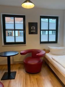 Schlafzimmer mit einem roten Stuhl, einem Bett und einem Fenster in der Unterkunft Double B in Erfurt
