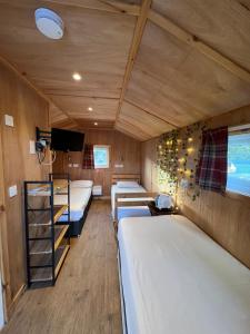 Habitación con 3 camas y TV. en Isle Of Skye Camping Pods, en Portree