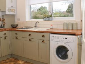 een keuken met een wasmachine en een wastafel bij Hope Cottage in Hambleton